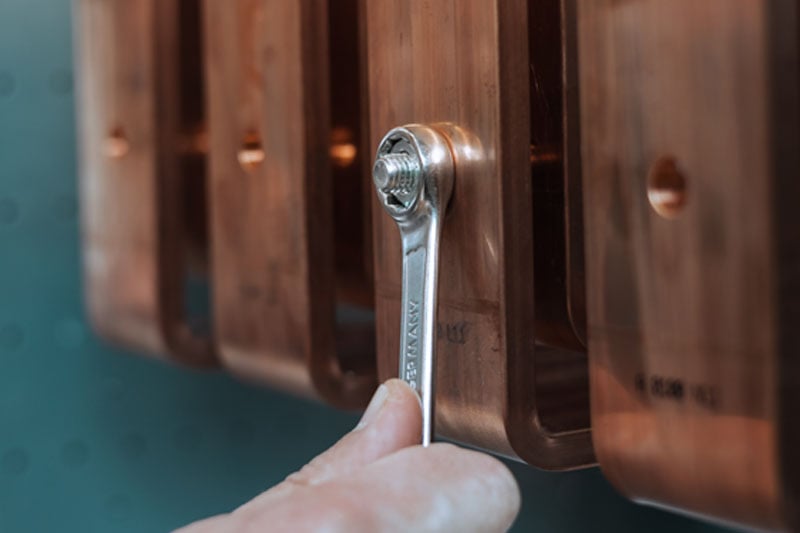 Schraube an einem Schaltschrank wird mit einem Schraubenschlüssel festgezogen